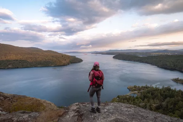 A person standing on a rocky ledge looking out over the ocean.