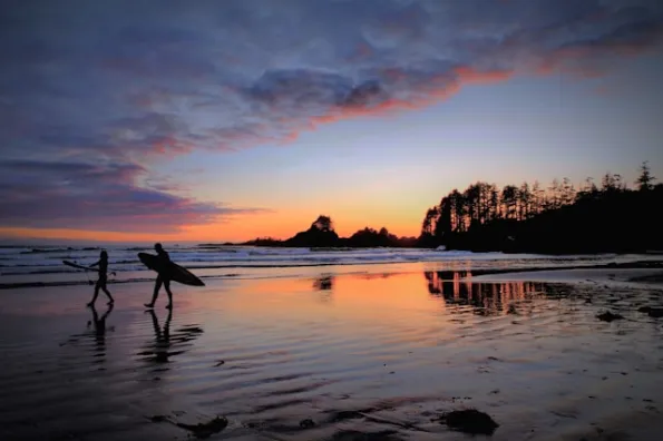 Ocean at sunset with two surfers walking on the beach