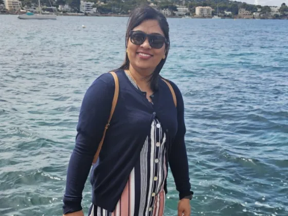 Hardeep standing in front of a body of water overlooking a city.